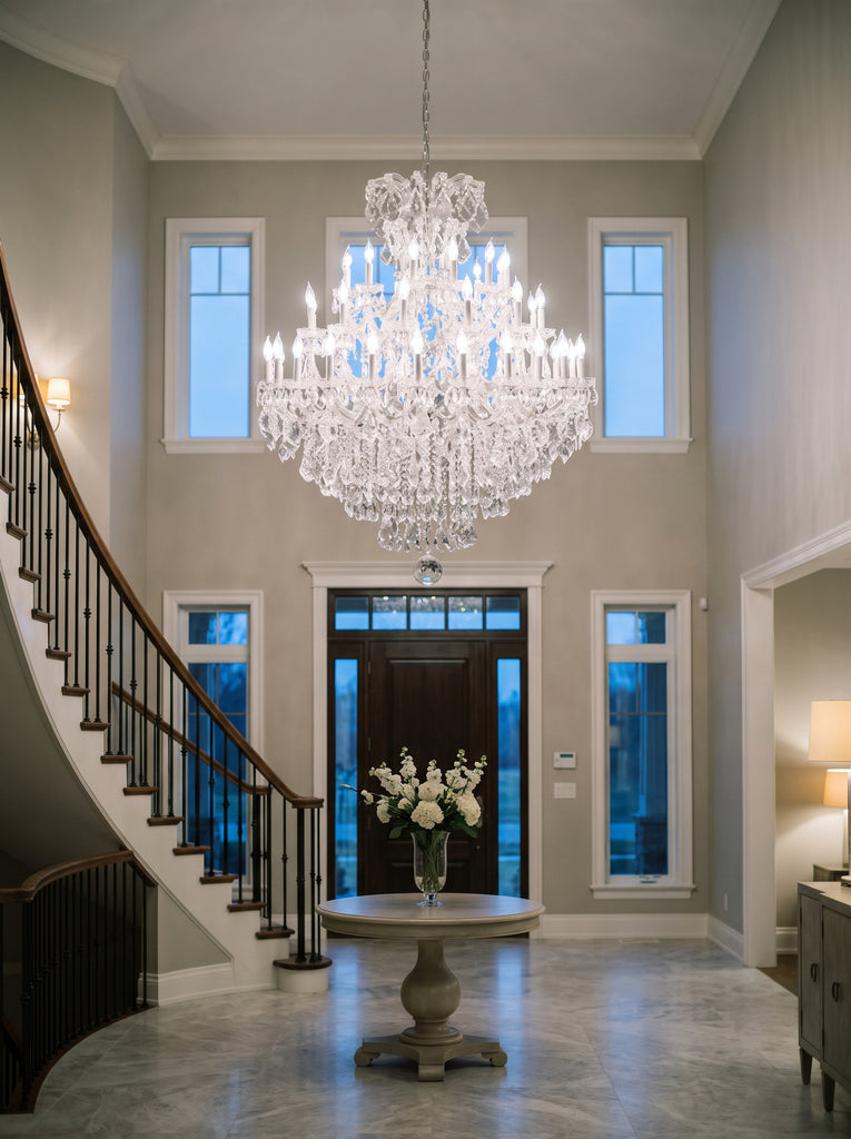 Maria Theresa Empress crystal chandelier in silver chrome finish hanging in a two-story foyer with curved staircase, 52 inches wide by 60 inches tall